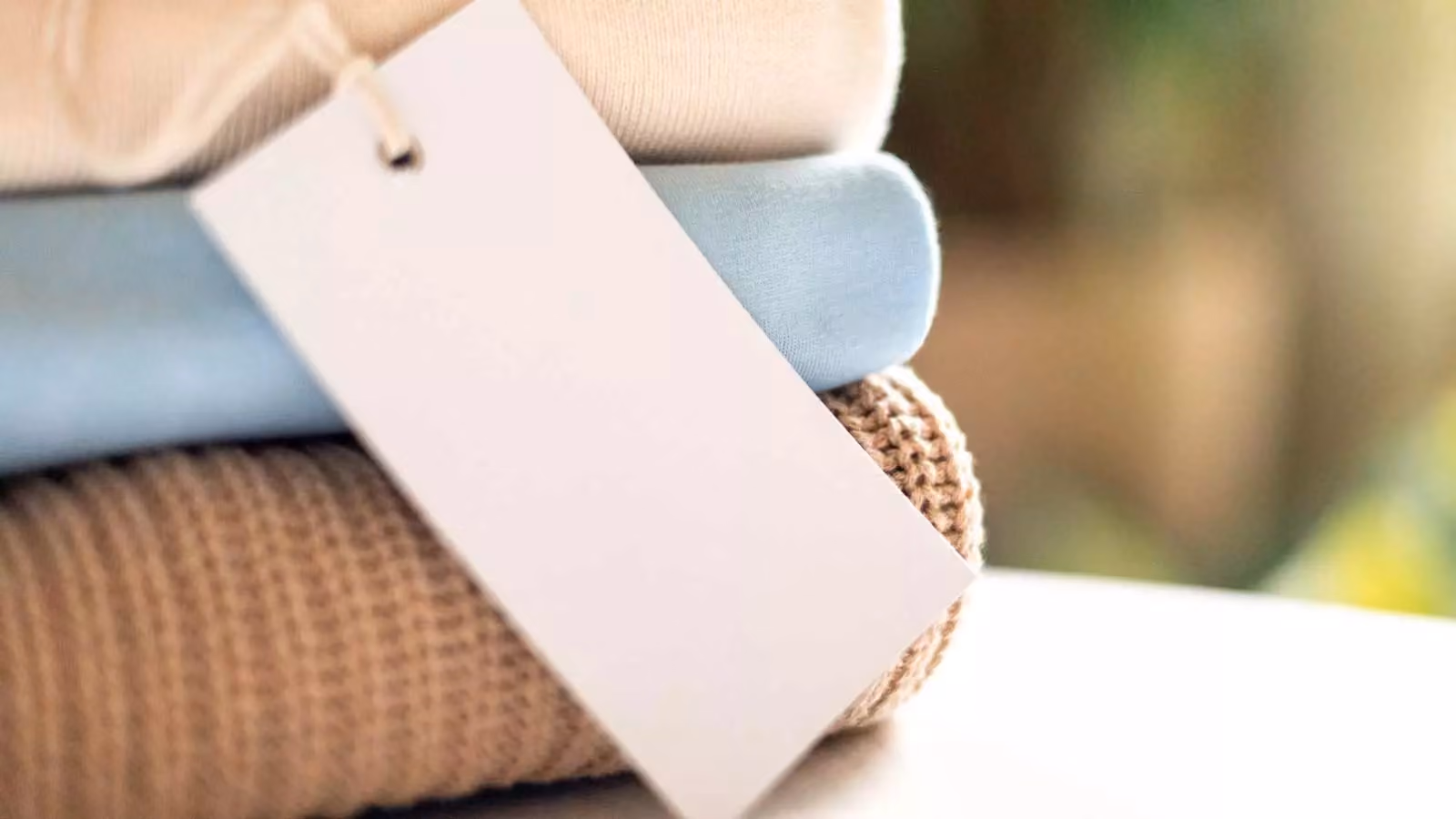 A stack of neatly folded knitwear with a white blank label. Visualization of efficient inventory management for seasonal products with high demand volatility in the fashion industry.