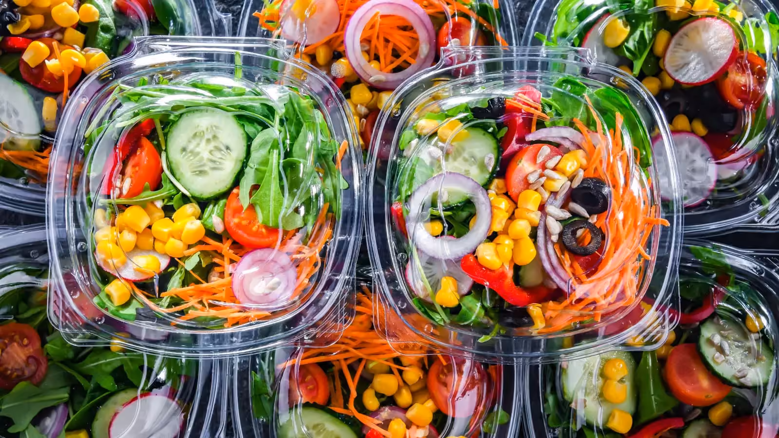 Fresh salad packs arranged in transparent containers. Supply chain optimization for food-related seasonal products with short shelf lives and varying seasonal demand.