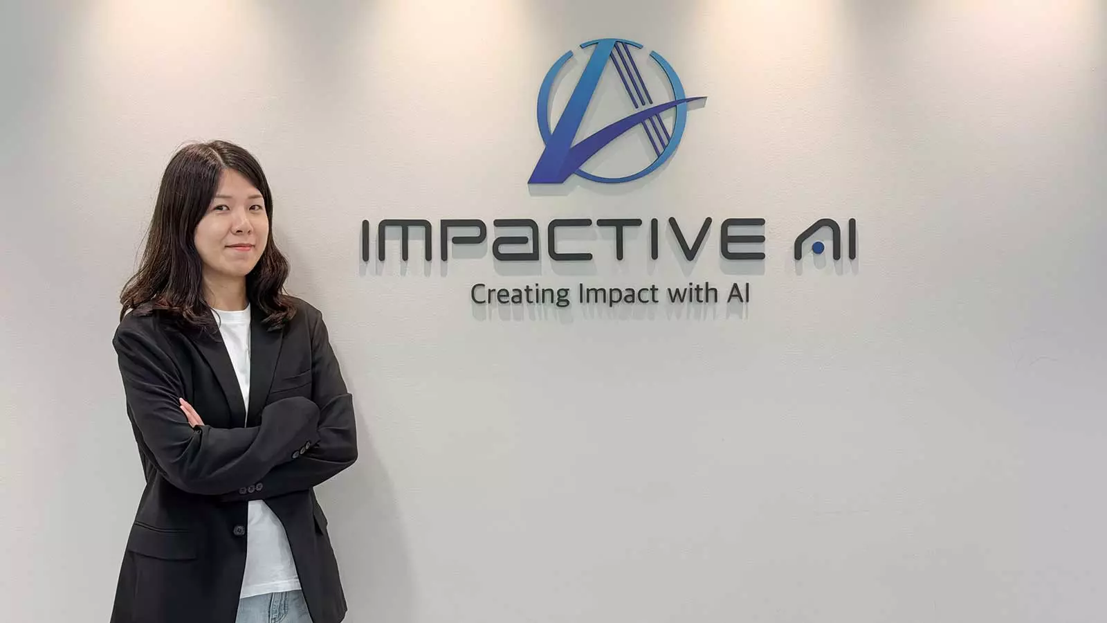 A portrait of an AI demand forecasting expert standing in front of the Impactive AI corporate logo wall.