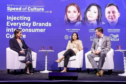 Three panelists seated on white chairs on stage discussing 'Injecting Everyday Brands into Consumer Culture' at Speed of Culture event.