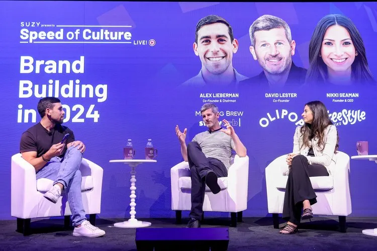 Three people sitting on white chairs on stage having a discussion at the SUZY Speed of Culture event about Brand Building in 2024.
