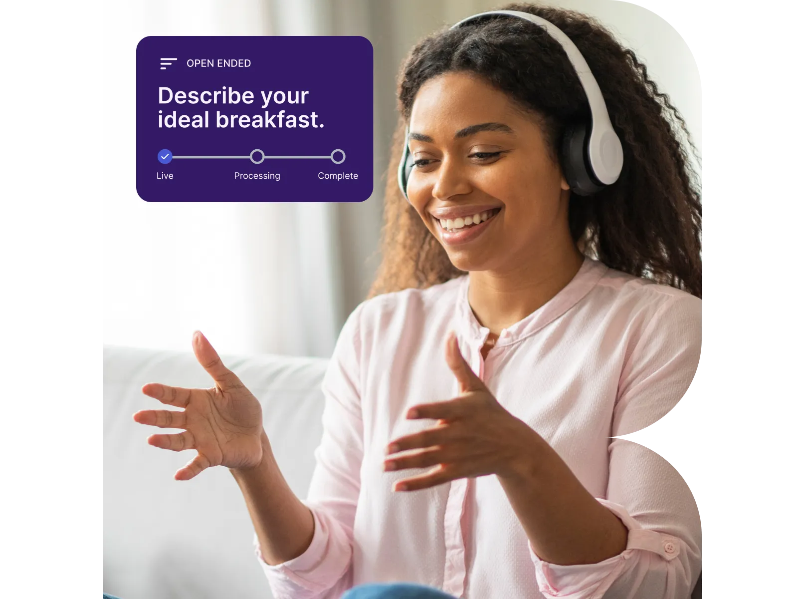 Smiling woman wearing headphones, gesturing with hands while responding to a prompt about describing her ideal breakfast.