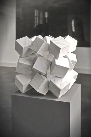 Sculpture of interlocking white cubes displayed on a gallery plinth