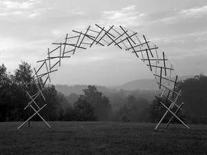 Arch of crossed timber poles standing in a misty field