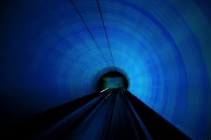 Curved tunnel washed in blue light with streaked reflections