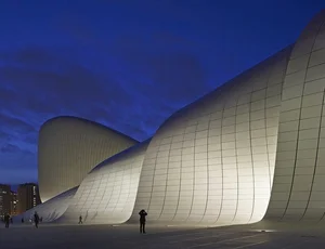 Sweeping white curved building lit against a deep blue dusk sky
