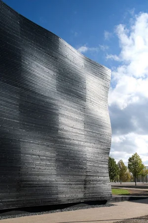 Curved concrete wall with horizontal striations under a bright sky