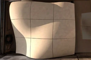 Curved beige panel mock-up standing in a fabrication workshop