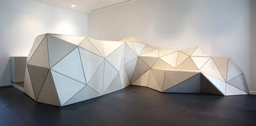 Faceted white folded surface installation running along a gallery wall