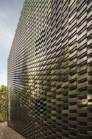 Facade of narrow stacked tiles shifting from green to bronze across the elevation