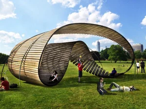 Curved timber slat pavilion on a park lawn with people resting inside