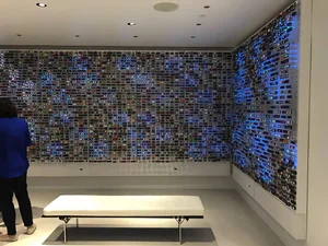 Wall of small square tiles forming a pixelated field of blues above a bench
