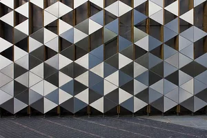 Facade tiled with triangular metal panels in shifting greys