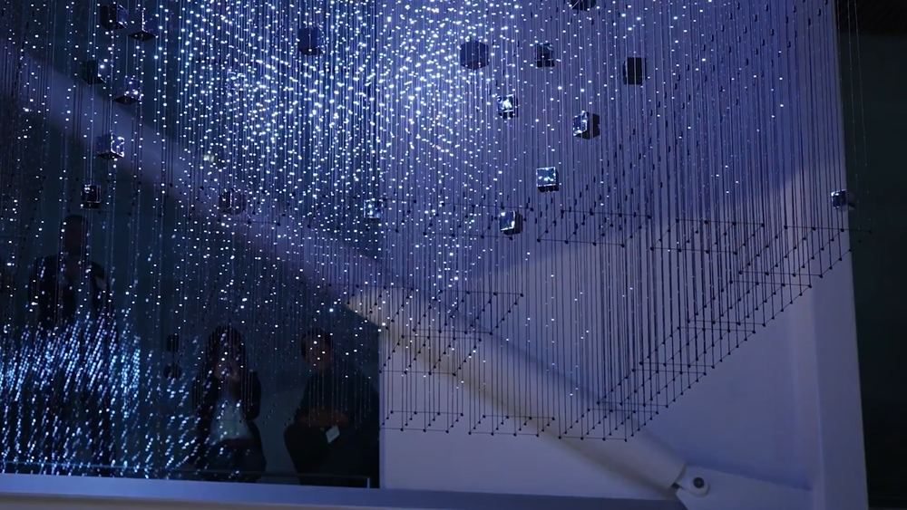 The Strauch Hypercube lit blue above visitors in the atrium below