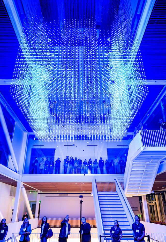 The Hypercube lit blue over the atrium staircase during an evening event
