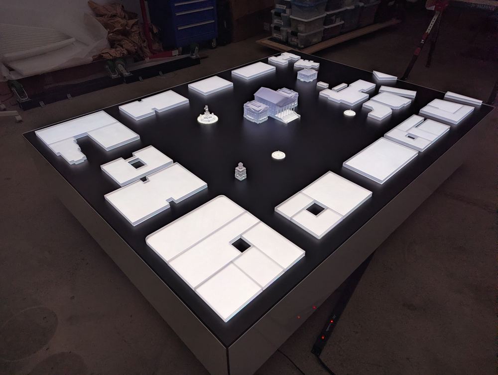 The Capitol table under fabrication, white acrylic pieces laid out on the black surface