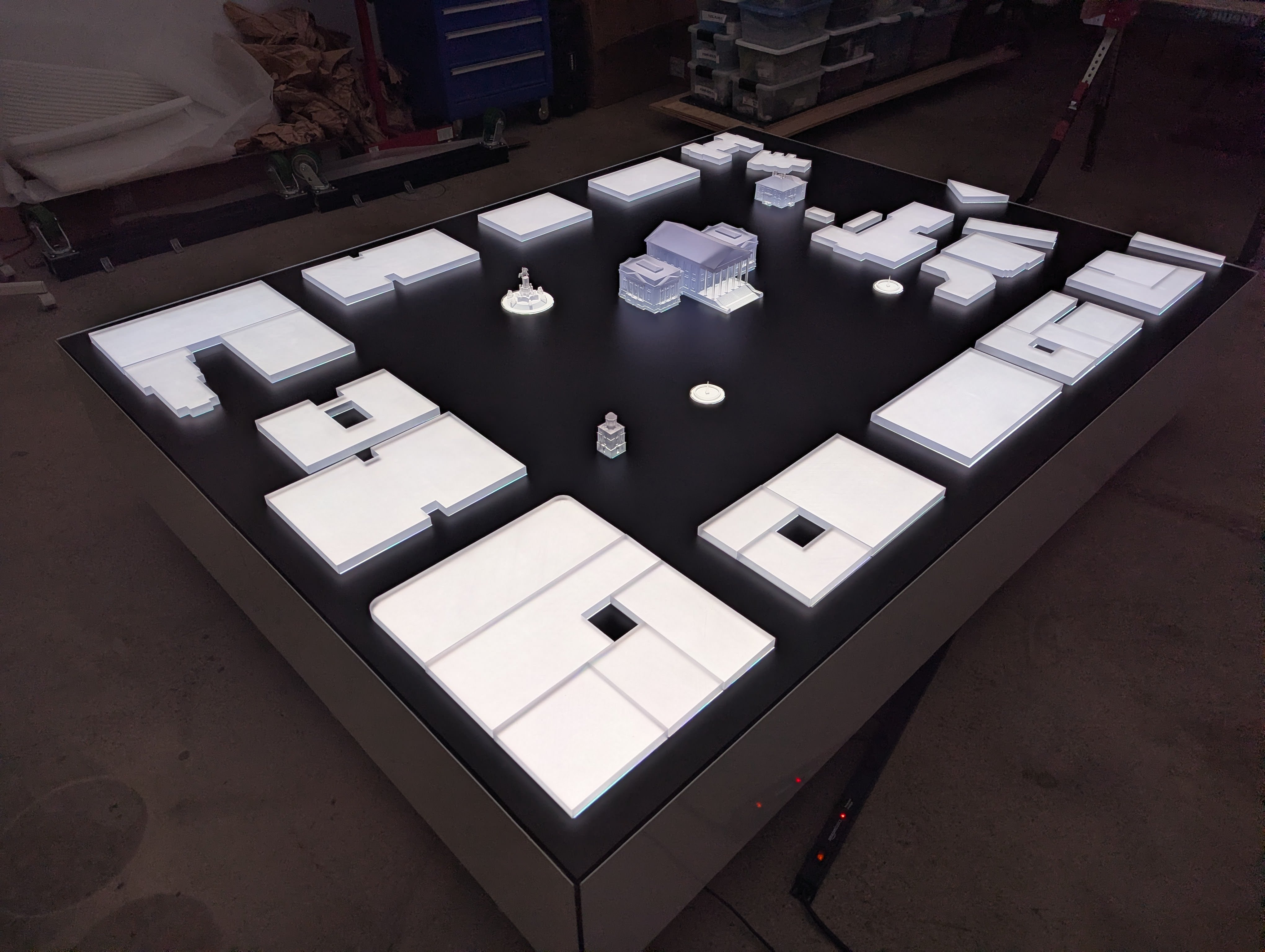 The Capitol table under fabrication, white acrylic pieces laid out on the black surface