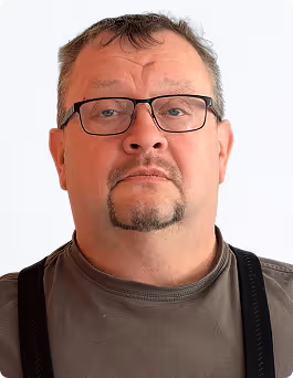 Porträt eines Mannes mittleren Alters mit Brille, kurzem Haar und grauem T-Shirt vor weißem Hintergrund.