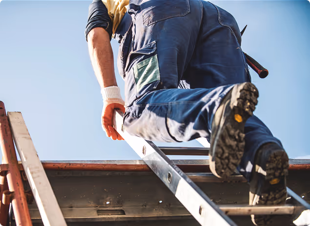 Eine Person in Arbeitskleidung klettert eine Leiter bei klarem Himmel hinauf.