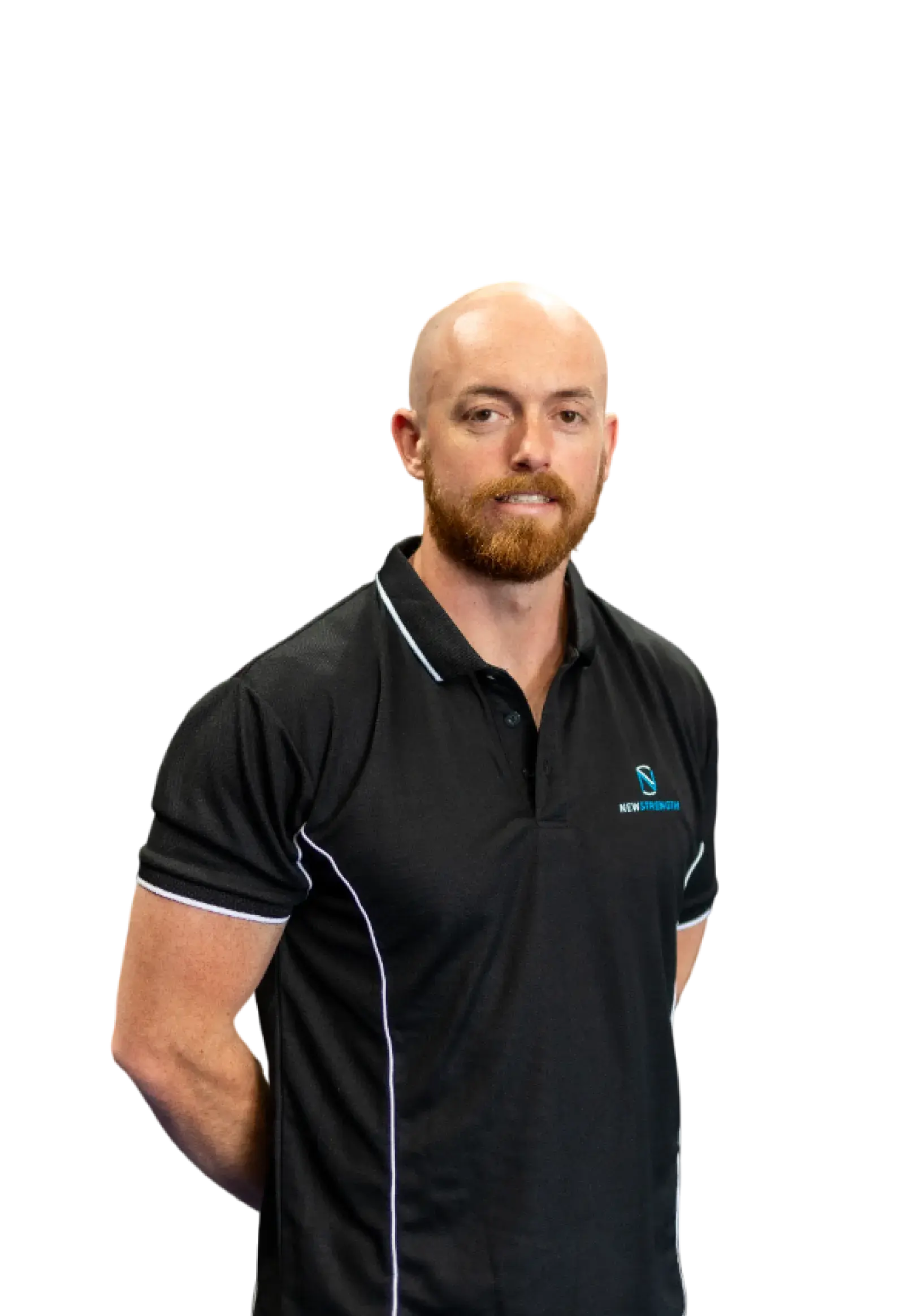 Bald man with a red beard wearing a black New Strength polo shirt standing with arms behind his back.