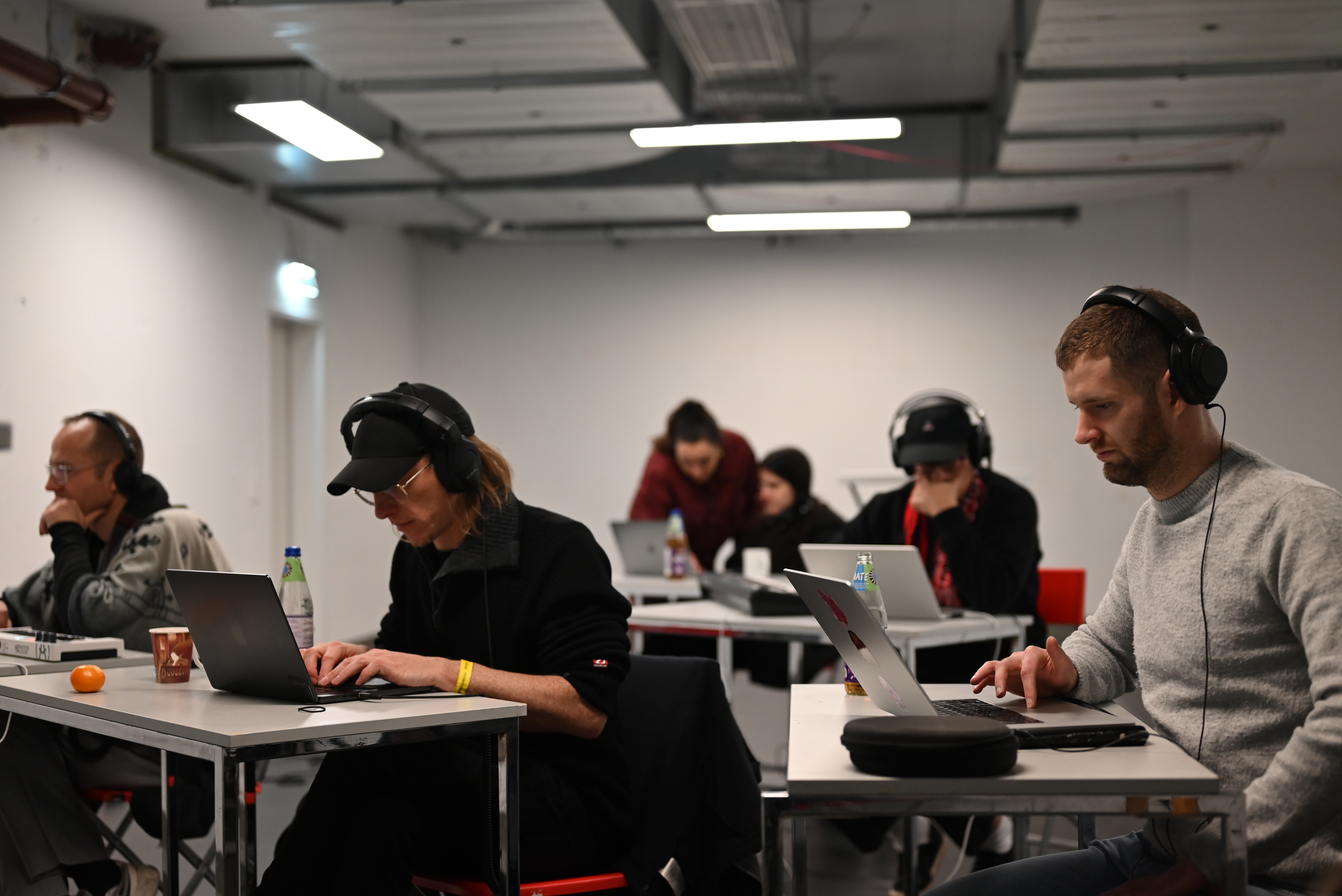Workshop room with six participants working individually on laptops with headphones