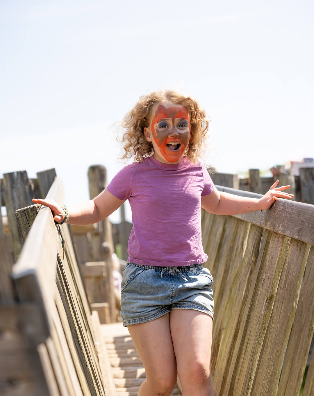 A beaver drinking water from a pond in a forest with a woman crouching nearby and a metal animal trap cage beside her.