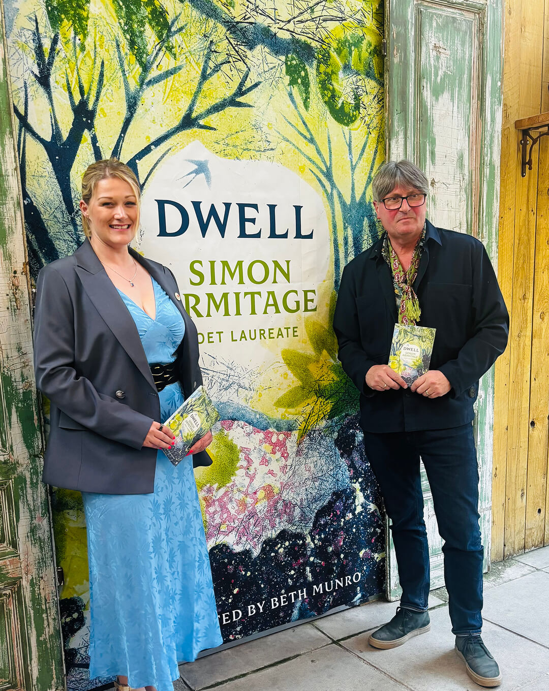A beaver drinking water from a pond in a forest with a woman crouching nearby and a metal animal trap cage beside her.