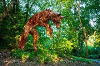 Large illuminated sculpture of a colorful kingfisher bird glowing against a dark night background.