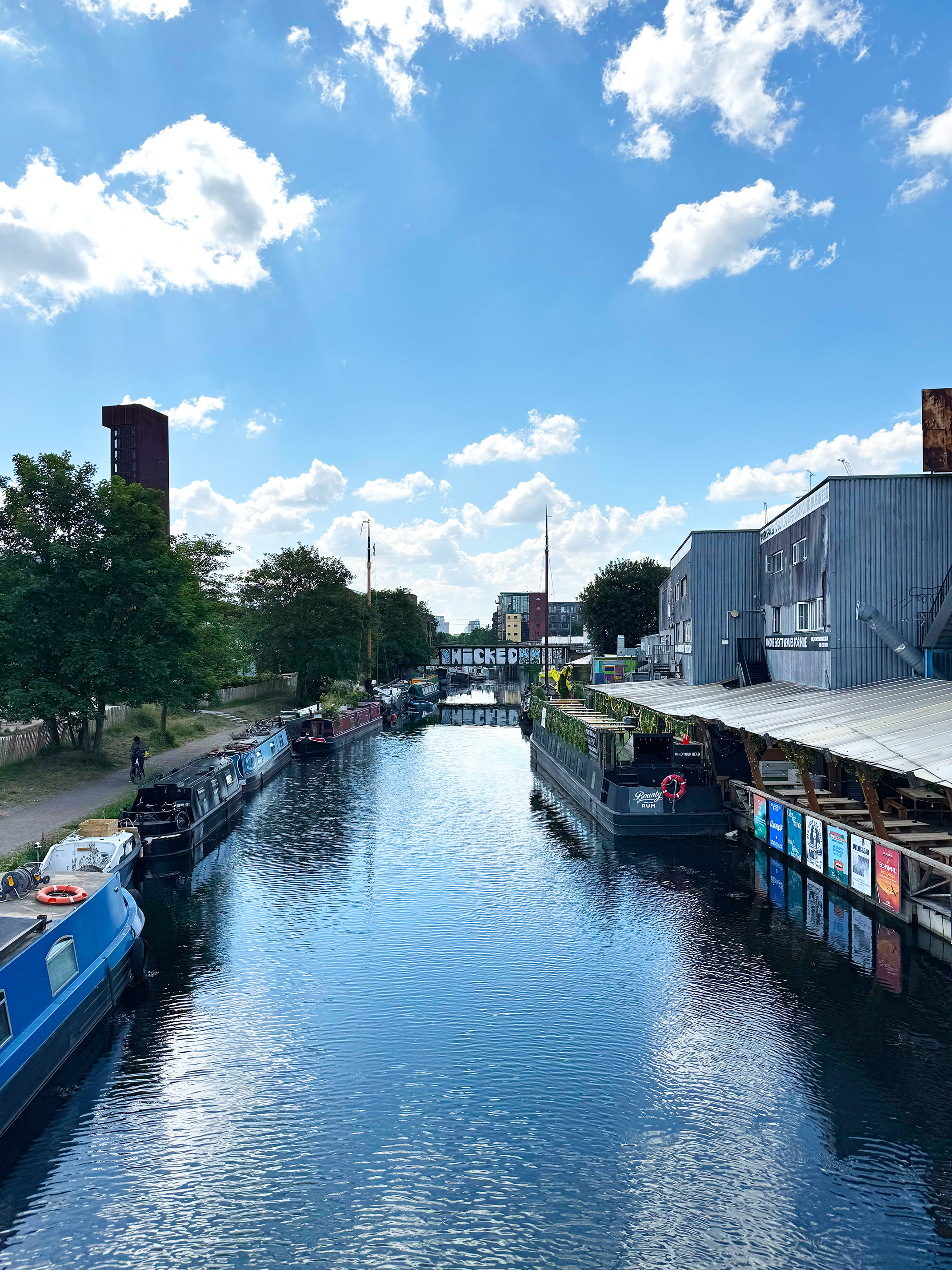 Hackney Wick canal with narrowboats and creative industrial buildings on a sunny day, East London