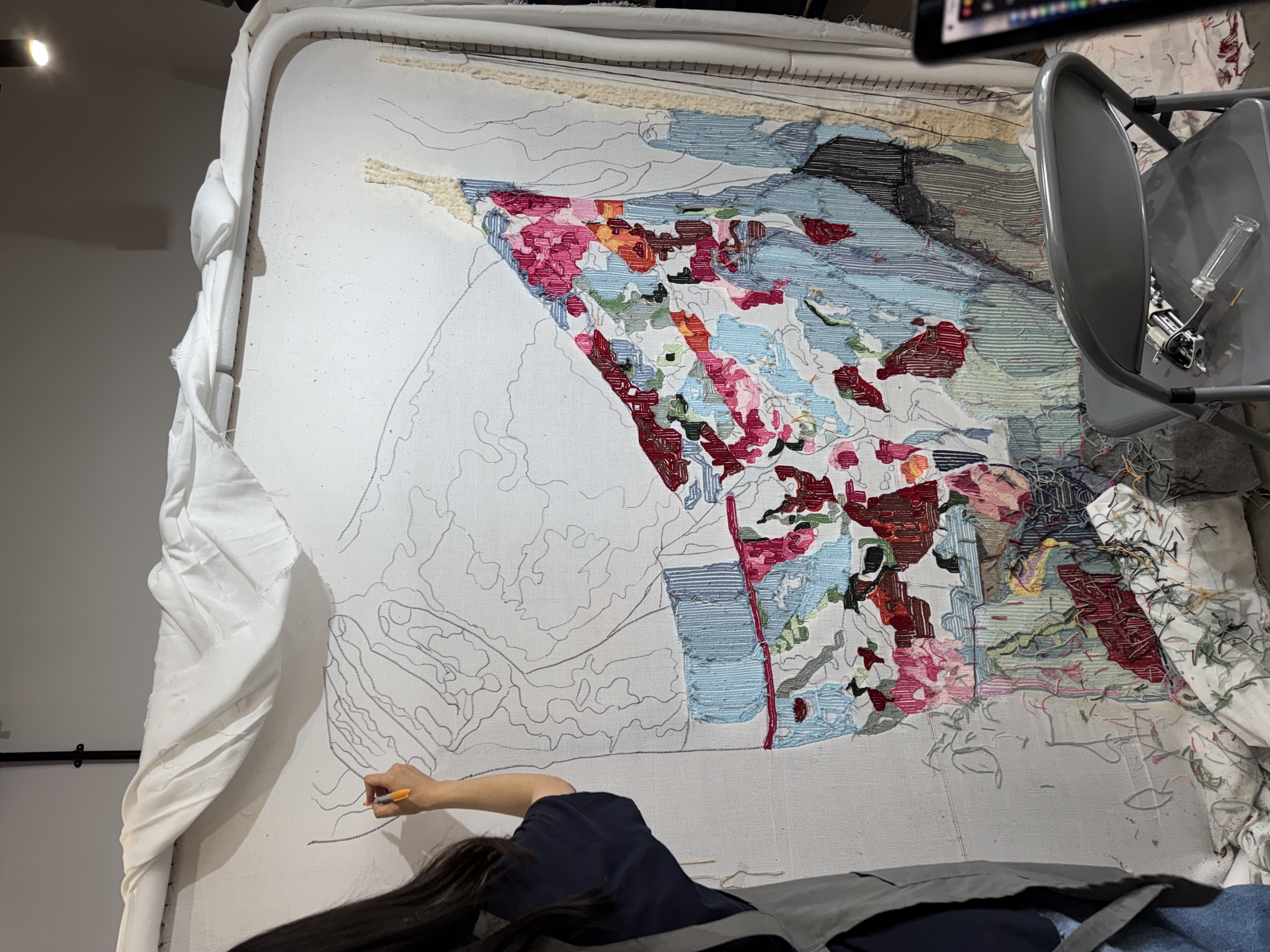 Jenny Kim, co-founder of Cheeky Studio, sketching the  Danny Dyer portrait onto the tufting canvas during the  making of the Sky TV Mr Bigstuff large-scale rug  commission, Hackney Wick London 2024