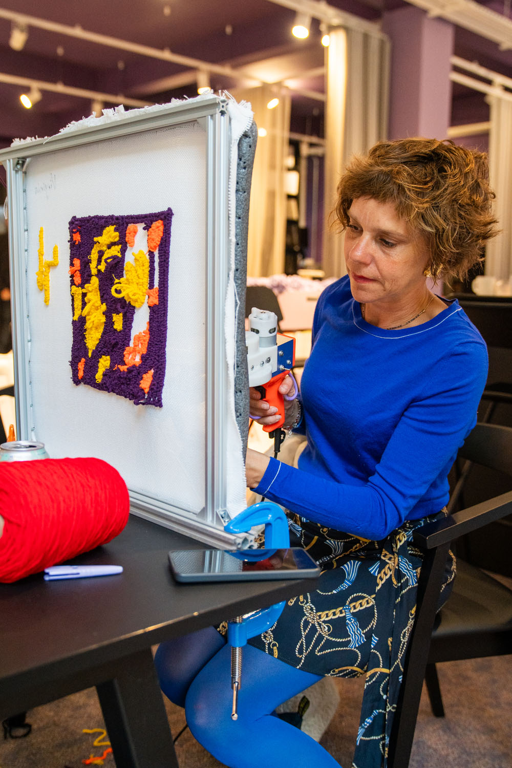 Workshop participant using a cut pile tufting gun to create a purple and yellow rug design at a Cheeky Studio session
