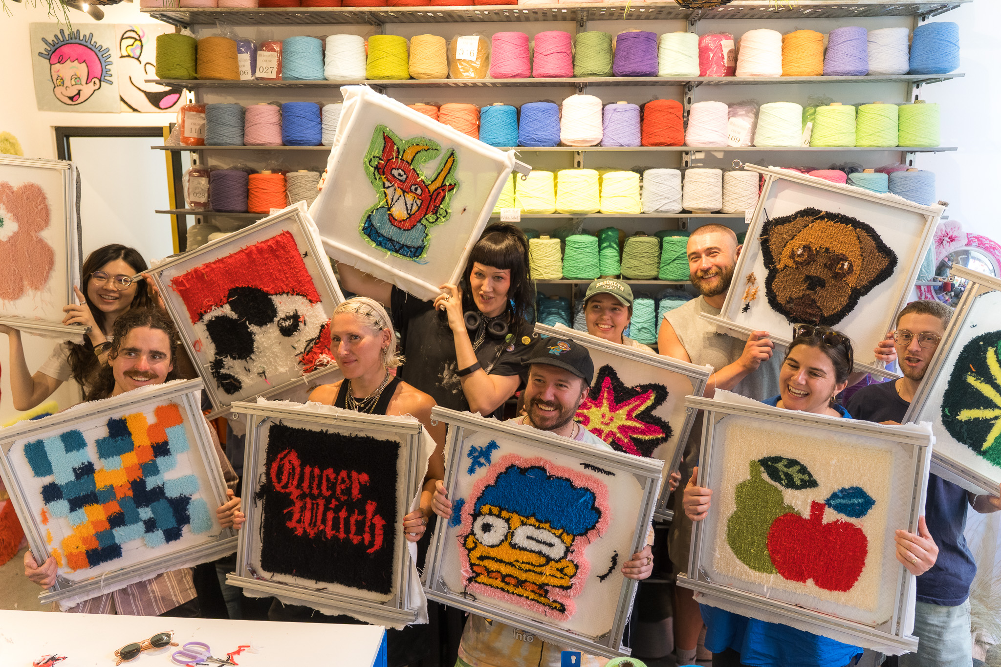 The whole Studio Moross team holding up their finished tufted rugs at the end of a team building workshop at Cheeky Studio in Hackney Wick