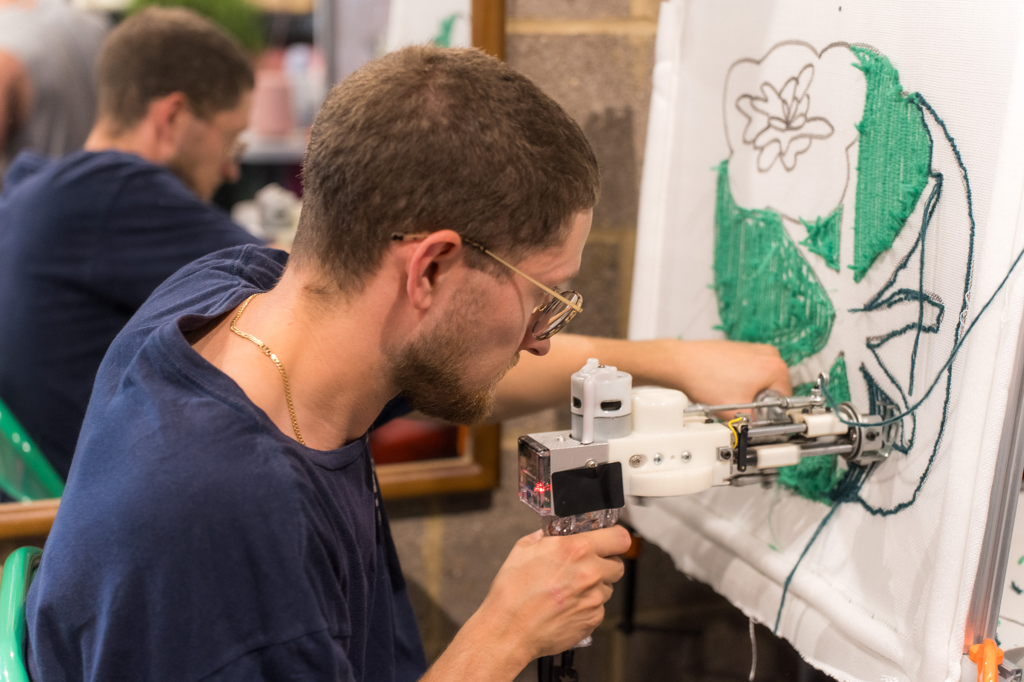 Man using a tufting gun to fill in a green design at a Cheeky Studio team building workshop in Hackney Wick