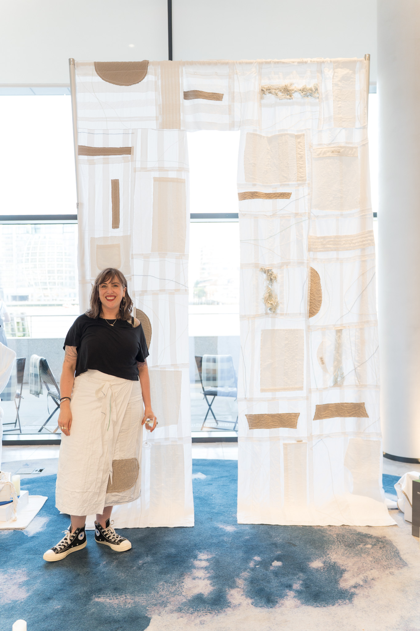 Textile artist standing beside the large Threads of Renewal installation at The Westin London City