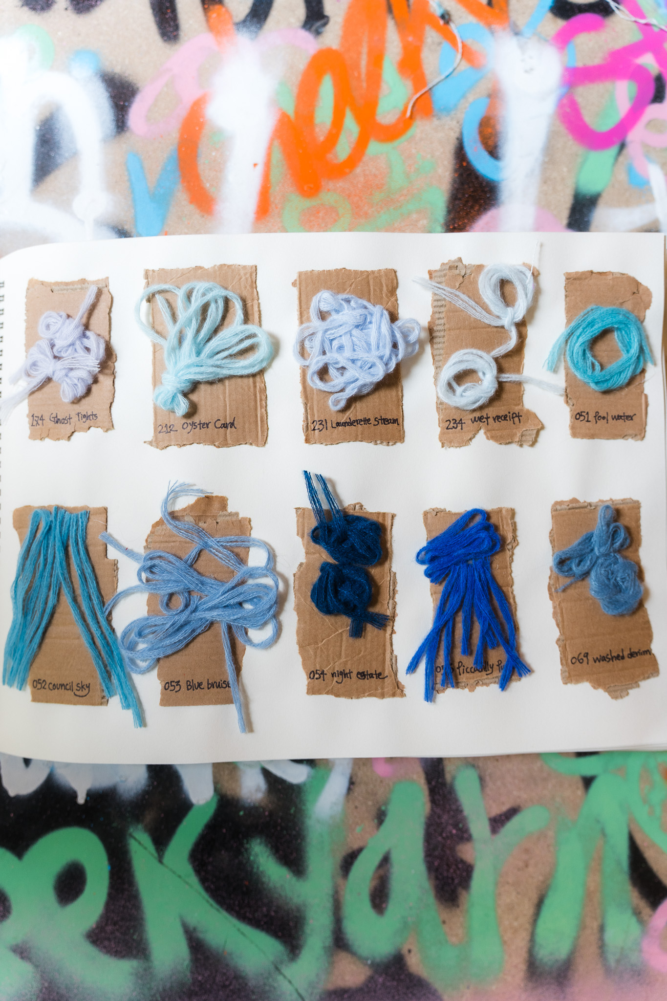 Handmade Cheekyarn sample book displaying blue recycled yarn colours with London-inspired names for tufting workshops