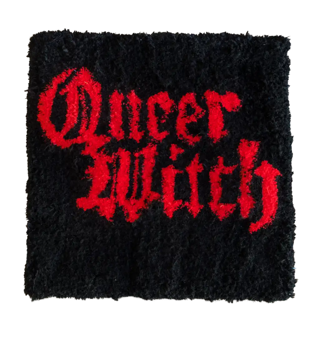Black square tufted rug with red Gothic lettering reading “Queer Witch”