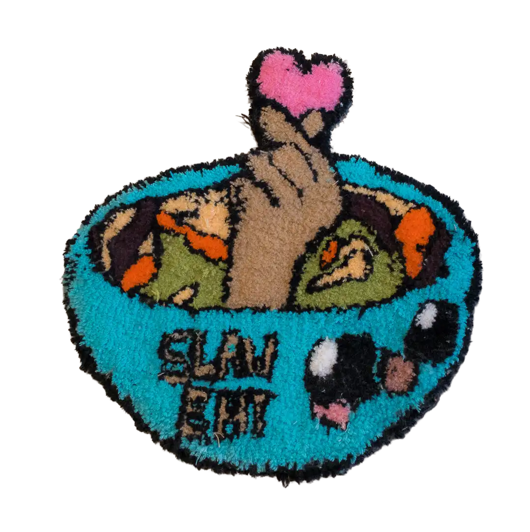 Turquoise bowl-shaped tufted rug with food illustrations, a finger-heart gesture and “SLAY EAT” lettering