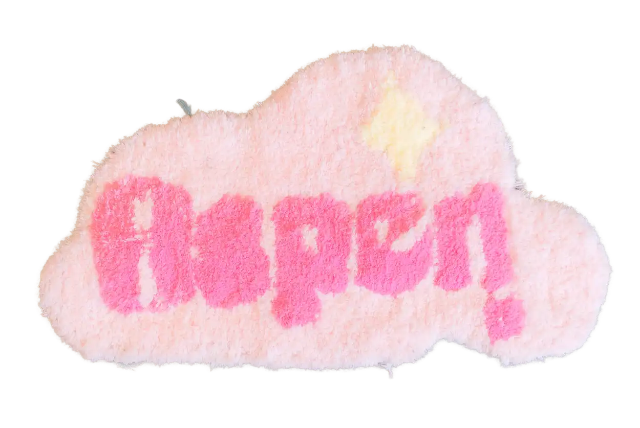 Pink cloud-shaped tufted rug with bright pink “Angel” lettering and a pale yellow sparkle