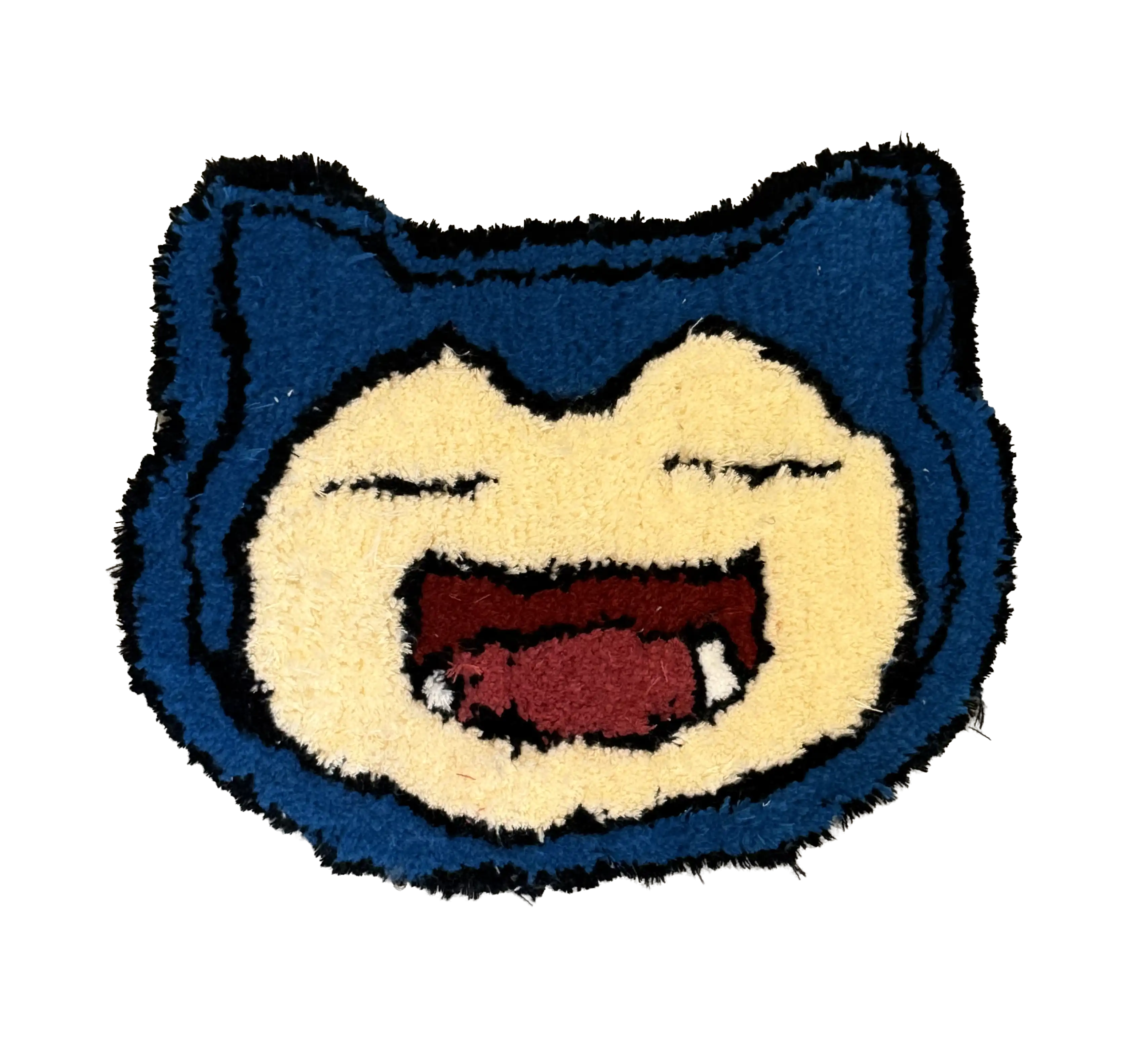 Blue cartoon creature face tufted rug with closed eyes, an open mouth and small white teeth
