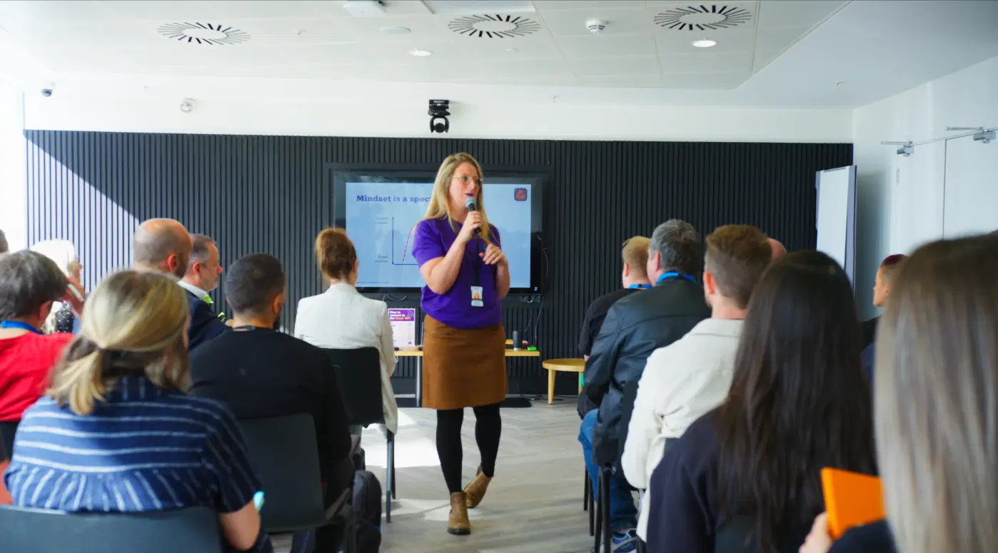 Capturing a professional workshop environment with a facilitator presenting to an engaged audience, showcasing corporate training video production.