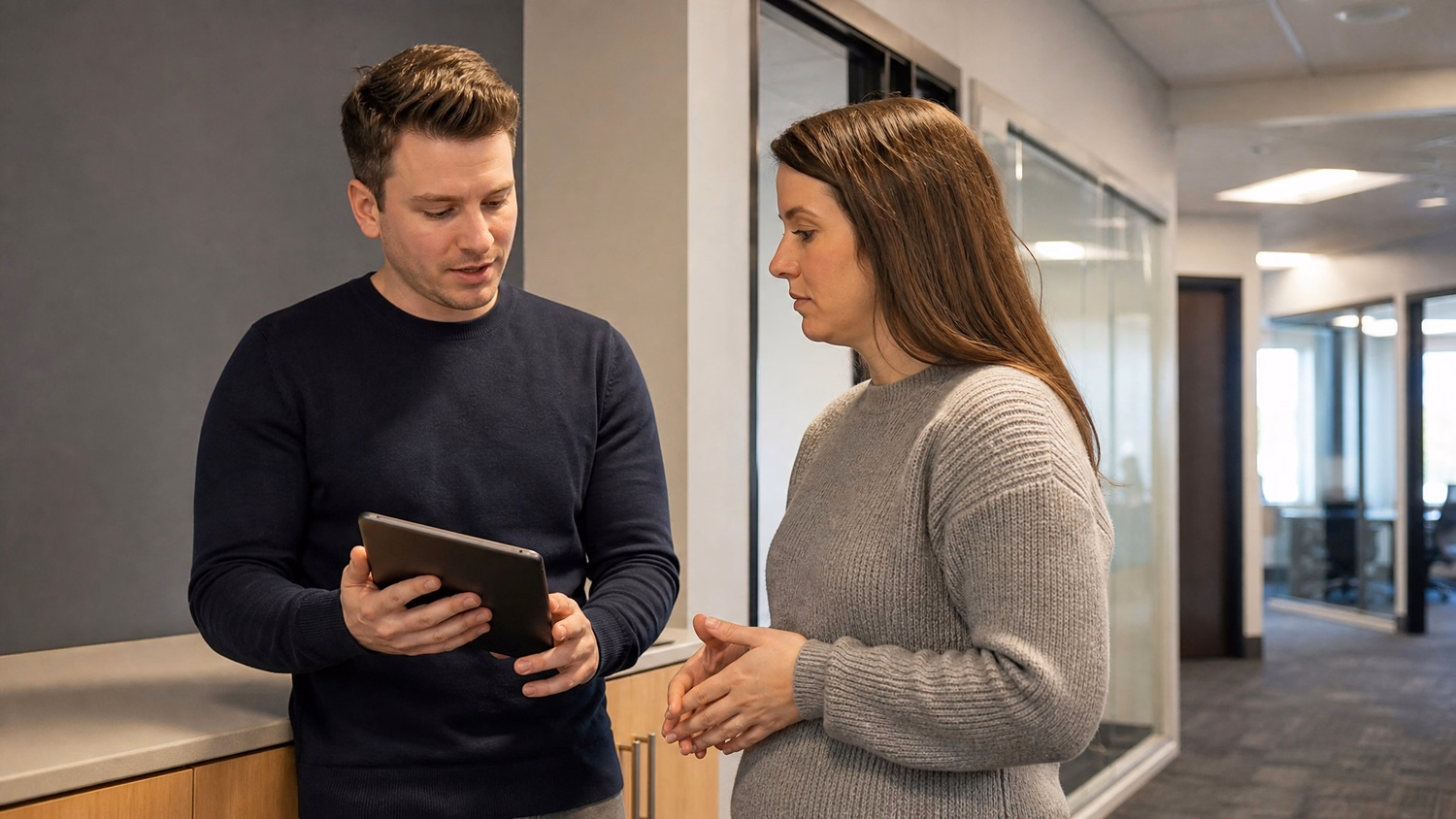 INFORMAL HUDDLE An IT professional  two people standing and talking near a ki