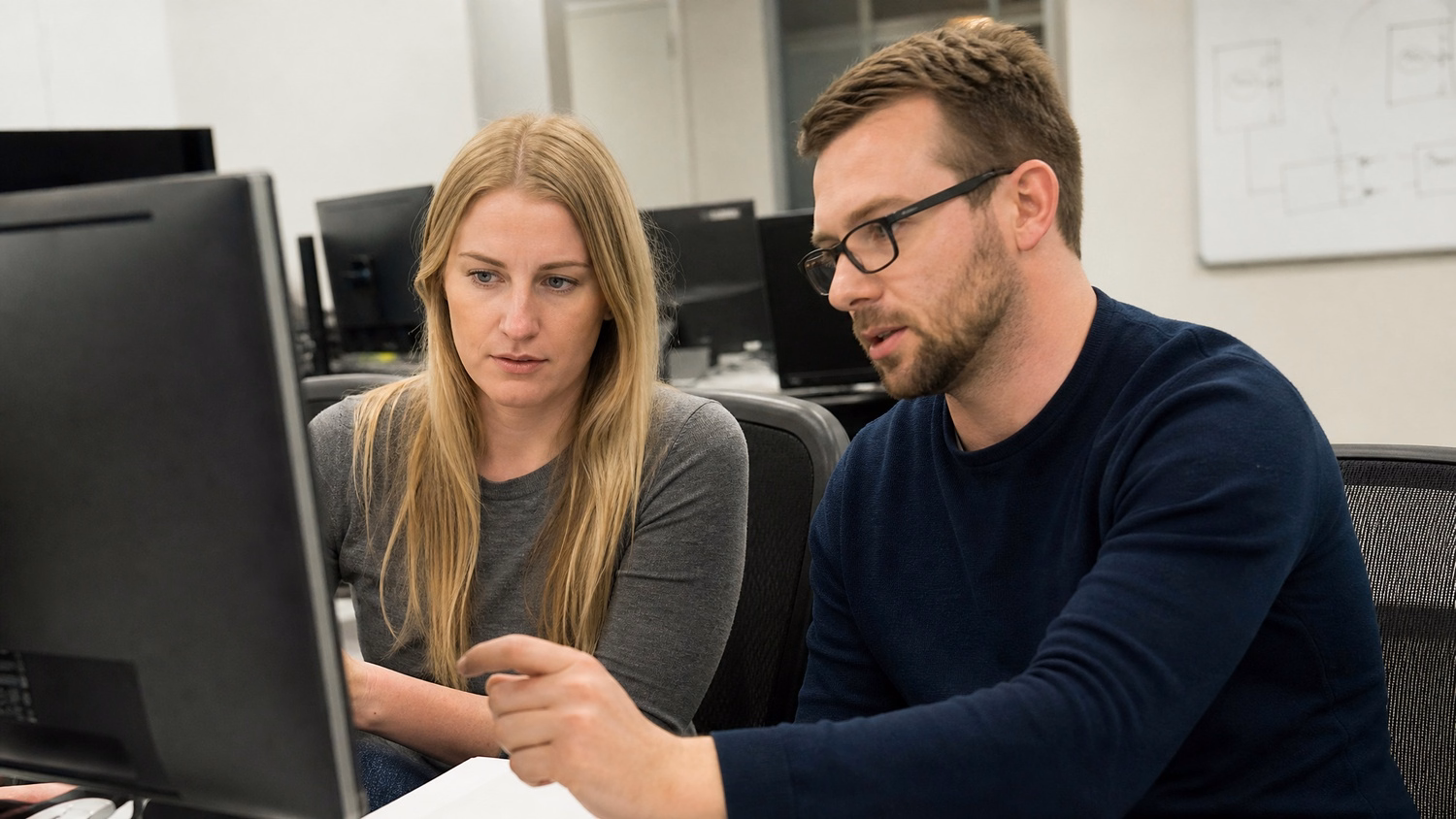 SIDE-BY-SIDE PAIR An IT professional two people seated side by side reviewin