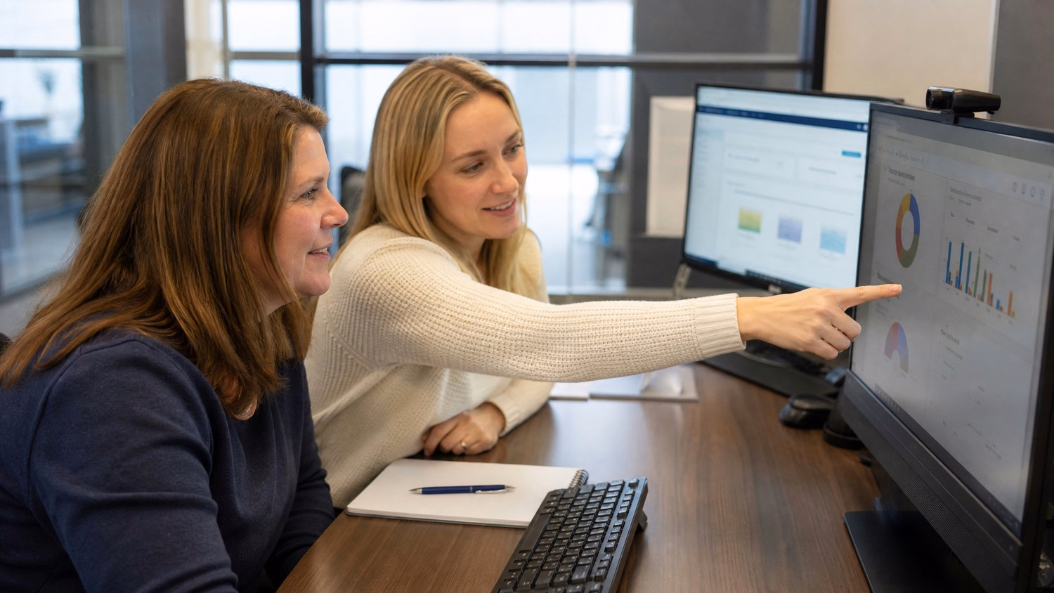 Two women review business growth roadmap on large monitor