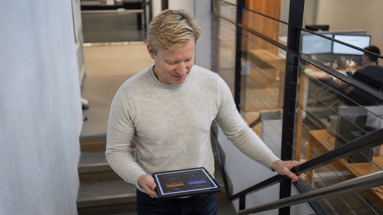 Man reviews financial chart on tablet in office stairwell