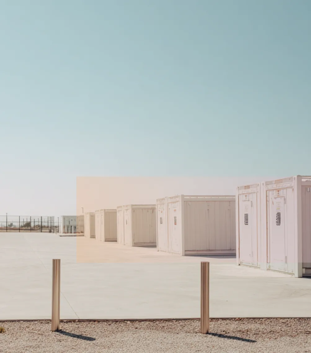 battey storage containers lined up on a large concrete surface under a clear blue sky.