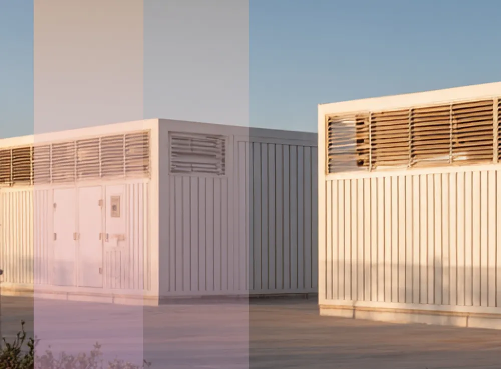 battey storage containers lined up on a large concrete surface under a clear blue sky.