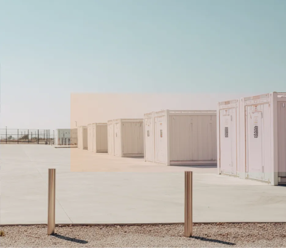battey storage containers lined up on a large concrete surface under a clear blue sky.