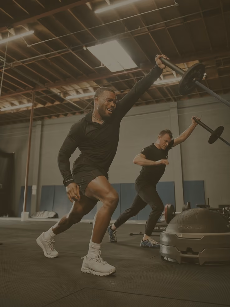 Two athletes training with barbells in a gym