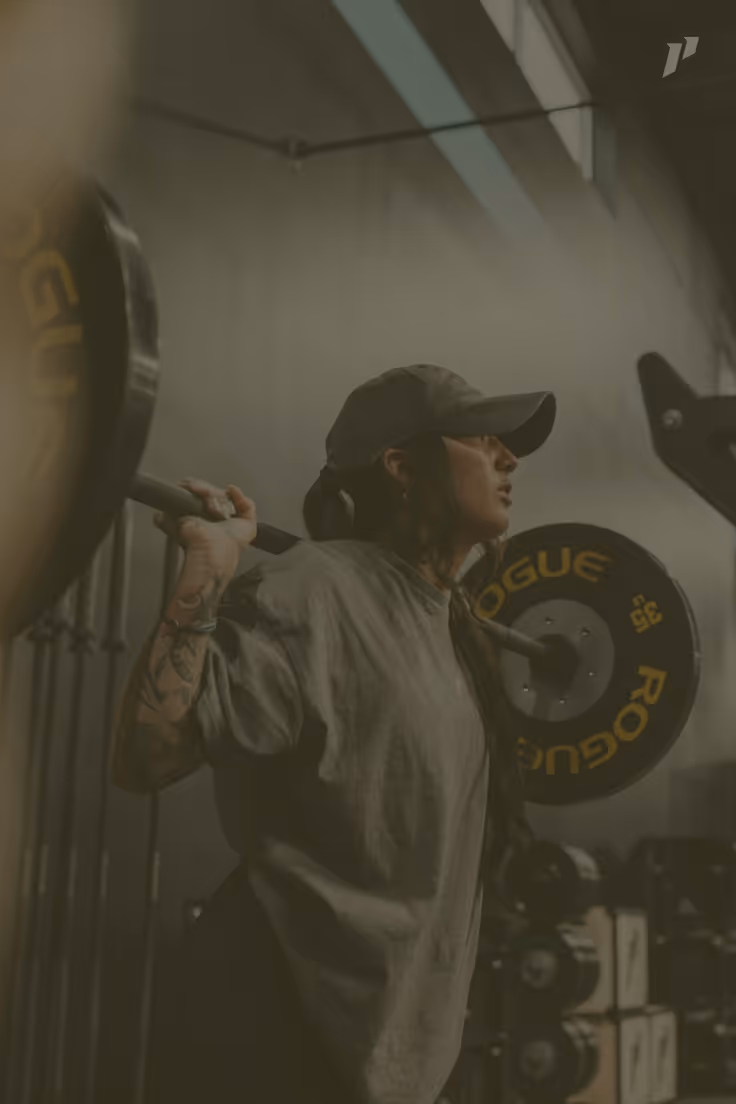 Woman in a cap lifting a barbell from the rack