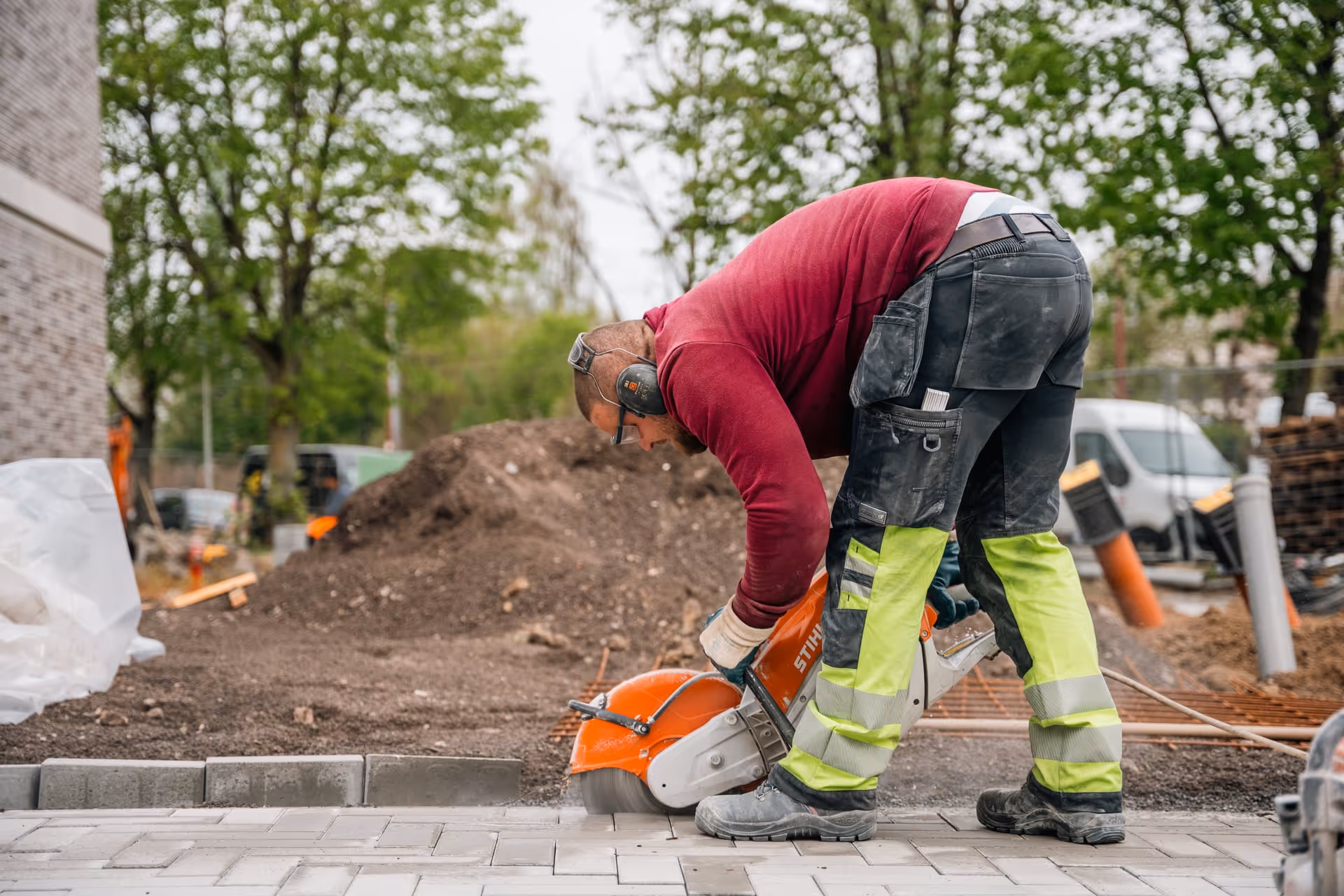 Een bouwvakker die buiten met een Stihl-betonzaag straatstenen zaagt.